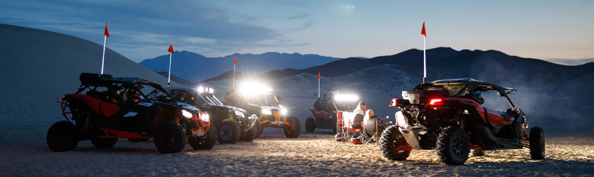 Four people riding 2020 Can-Am® UTVs through a hilly area